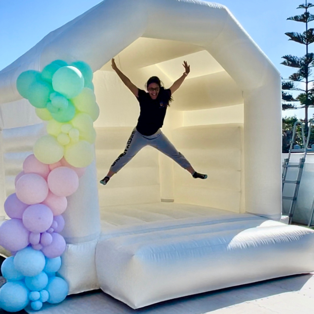 White bouncy castle with girl jumping and having fun