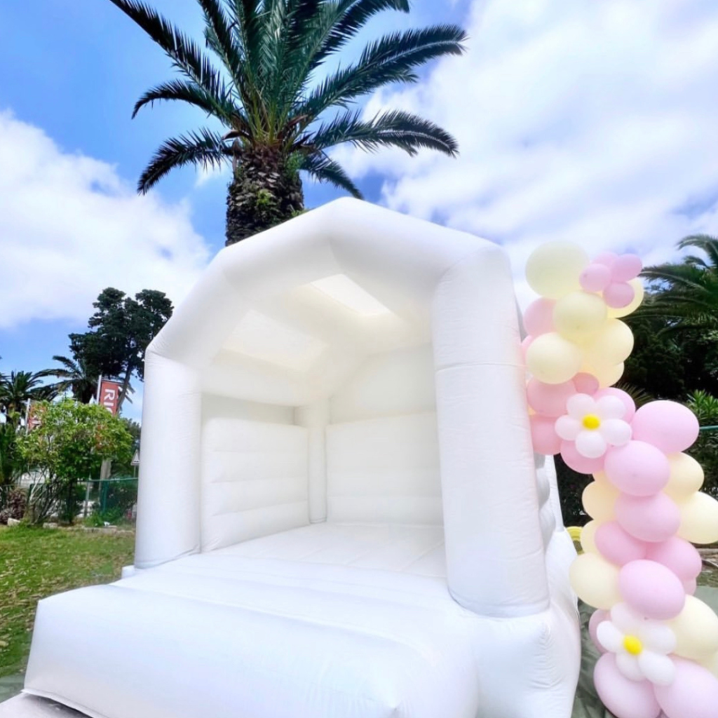 White bouncy castle decorated with pastel color balloons